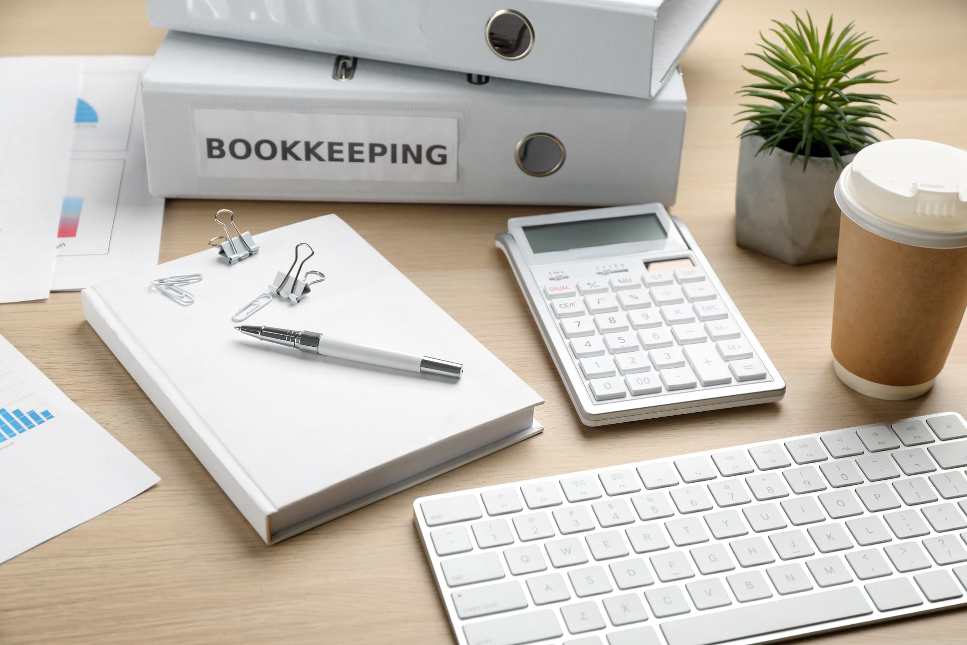 Bookkeeping binder, calculator, keyboard and financial reports on an office desk